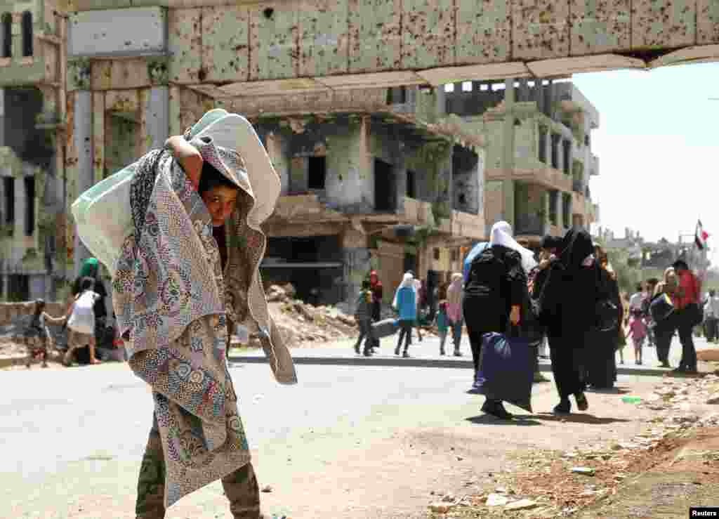 A boy holds his belongings as he returns to his neighborhood in Deraa al Balaad, Syria.