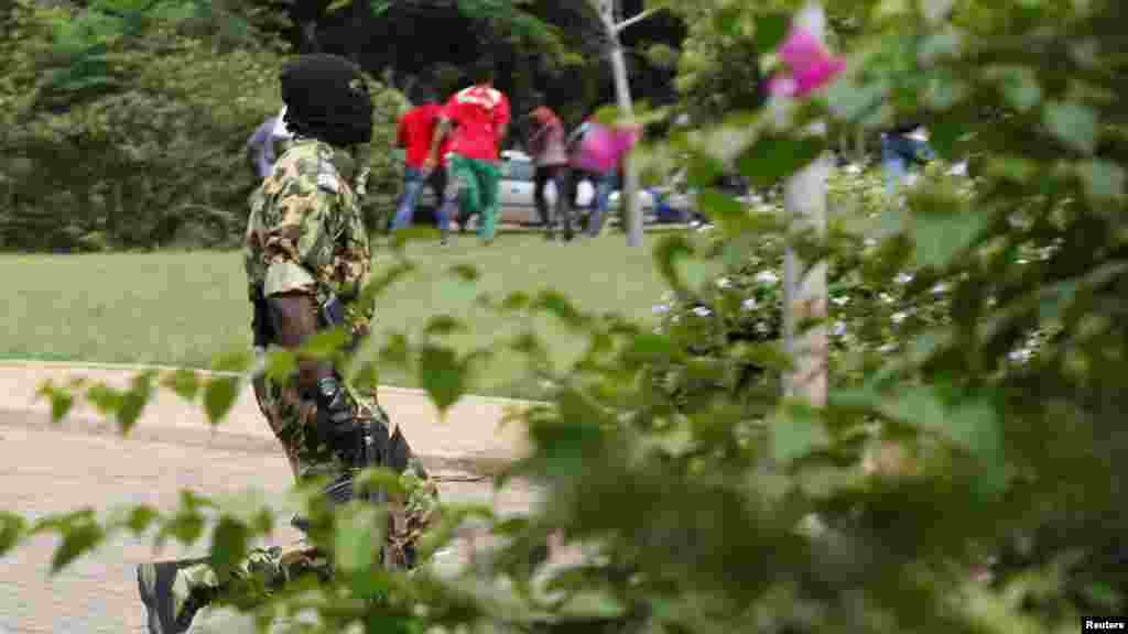 Un élément du Régiment de la sécurité présidentielle, visage masqué, s'avance en direction des manifestants qui s'en fuient à l'hôtel Laico à Ouagadougou, au Burkina Faso, 20 septembre 2015.