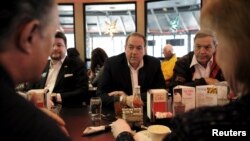 U.S. Republican presidential candidate Mike Huckabee, center, eats lunch with supporters, including former Congressman Duncan Hunter, right, at Drake Diner in Des Moines, Iowa, Feb. 1, 2016. 