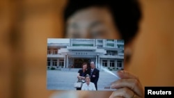 FILE - Kim Young-ja, a sister of Kim Young-nam who is a South Korean abductee living in North Korea, poses for photographs with a picture showing her abducted brother (R, in picture) taken during a reunion in 2006, July 2, 2014.