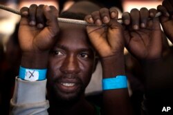 FILE - Samuel, 25, from Nigeria, waits his turn to leave the Golfo Azzurro rescue vessel as it arrives at the port of Pozzallo, south of Sicily, Italy, with hundreds of migrants aboard, rescued by members of Proactive Open Arms NGO, June 17, 2017.