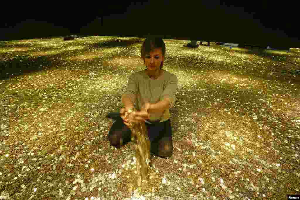 Sonja Enz of the Stapferhaus, an event place for contemporary exhibitions, holds coins in her hands as she sits in a room filled with four million Swiss five-cent coins during a media preview of the exhibition &quot;Geld - Jenseits von Gut und Boese&quot; (Money - Beyond Good and Evil) in the town of Lenzburg west of Zurich, Switzerland.