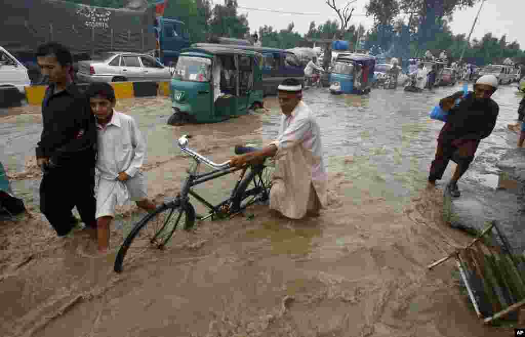 People and vehicles pass on a road flooded by heavy territorial rains in Peshawar, Pakistan, August 3, 2013.