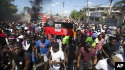 Manifestantes sostienen una antigua bandera haitiana con una imagen del héroe de la independencia, Jean Jacques Dessallines, en Puerto Príncipe, Haití, el miércoles 17 de octubre de 2018. 