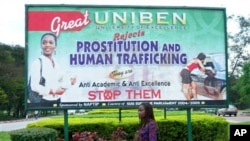 A student at Nigeria's Benin University in Benin City walks past a billboard encouraging women to fight prostitution and human trafficking.