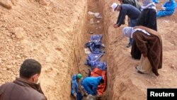 FILE - Men excavate remains of more than 25 men reportedly killed by Islamic State fighters on the outskirts of Saadia in Iraq's Diyala province, Jan. 15, 2015. 