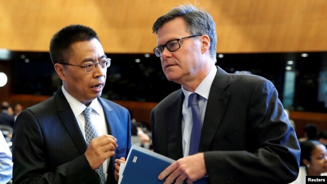 资料照片：美国驻WTO大使谢伊(右)在瑞士日内瓦举行的世界贸易组织（WTO）会议上与中国驻WTO大使张向晨交谈。（2018年7月26日）