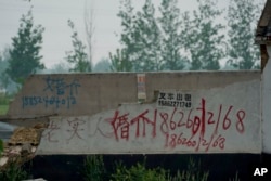 FILE - In this April 29, 2019, photo, graffiti advertising a marriage agent is spray-painted on the wall of a warehouse in Pei County in eastern China's Jiangsu province.