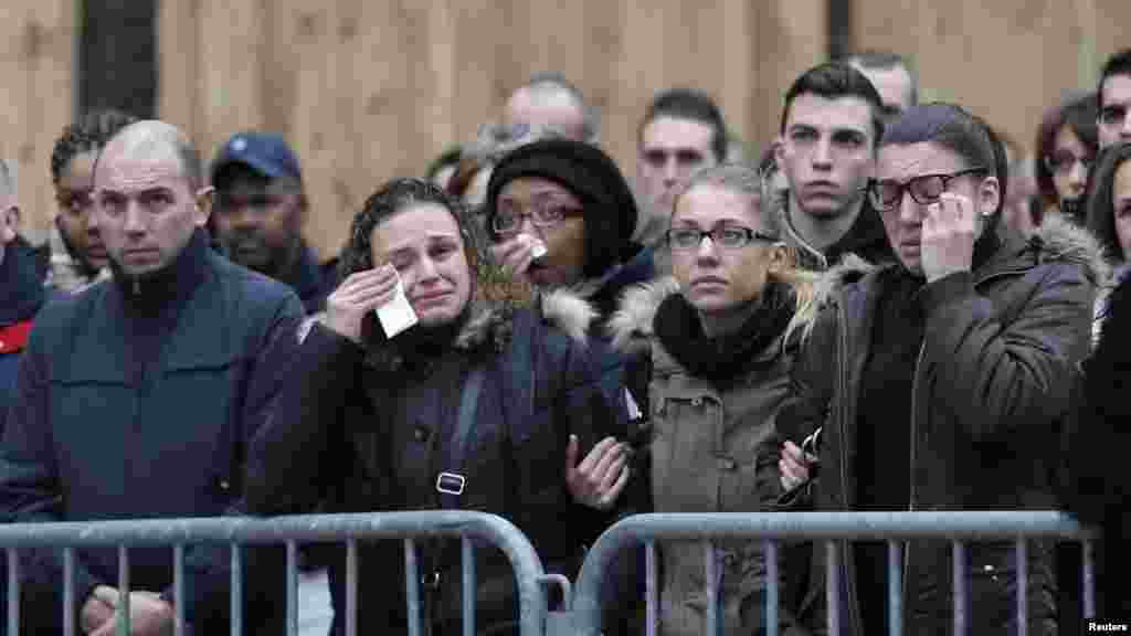 People react as they attend a national tribute for the three officers killed during last week's terrorist attacks, in front of Paris Prefecture, Jan. 13, 2015. 
