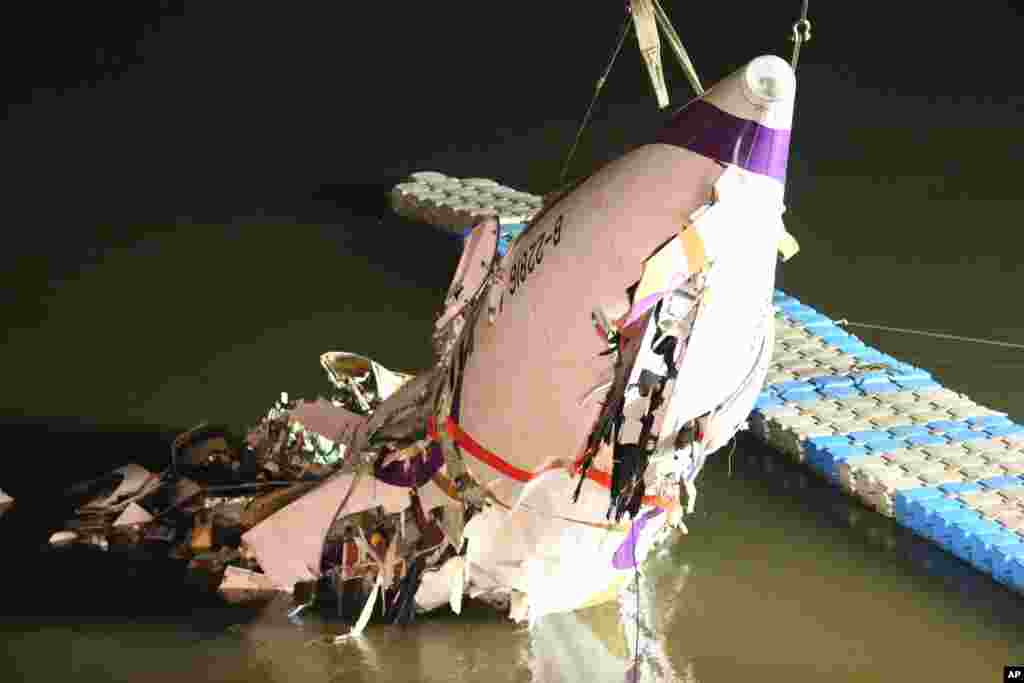 The mangled fuselage of a TransAsia Airways commercial plane is dragged to the river bank after it crashed in Taipei, Taiwan.