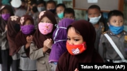 Children wear masks in the wake of the outbreak of a new coronavirus at a kindergarten in Jakarta, Indonesia, Thursday, March 5, 2020. Parents are deciding how to discuss the virus with their children.