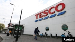 Seorang pria berjalan melewati sebuah toko Tesco di selatan kota London (23/10). Pemimpin perusahaan ritel raksasa Inggris ini, Richard Broadbent, menyatakan akan meletakkan jabatan, setelah ditemukan adanya selisih dalam laporan keuangan Tesco.