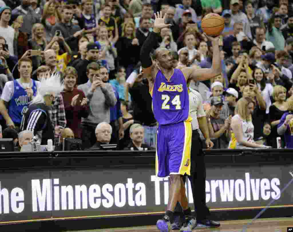 Los Angeles Lakers guard Kobe Bryant (24) holds up the game ball and acknowledges the crowd during an NBA basketball game against the Minnesota Timberwolves after passing Michael Jordan on the NBA all-time scoring list, in Minneapolis, Dec. 14, 2014.