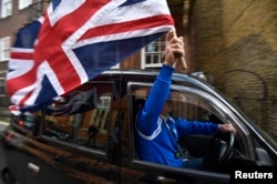 A taxi driver holds a Union flag, as he celebrates following the result of the EU referendum, in central London, Britain June 24, 2016.