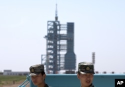 Chinese soldiers stand guard near the assembly of the Long March 2F rocket and the Shenzhou 10 spacecraft at the Jiuquan Satellite Launch Center in Jiuquan, China. June 11, 2013. (CREDIT/AP)