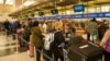 Passengers line up at John F. Kennedy International Airport after airlines announced numerous flights were canceled during the spread of the Omicron coronavirus variant on Christmas Eve in New York, Dec. 24, 2021.