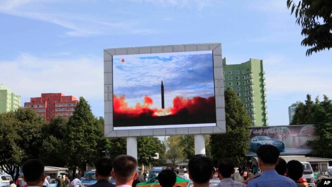 İnsanlar Pxenyanın dəmir yolu stansiyasının yerləşdiyi meydanda ballistik strateji raket sınağının televiziyada görüntülərini izləyir