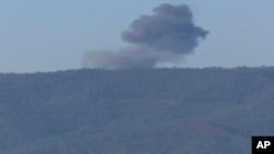 This frame grab from video by Haberturk TV, shows smoke from a Russian warplane after crashing on a hill as seen from Hatay province, Turkey, Nov. 24, 2015. 
