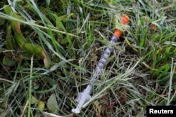 A used needle sits on the ground in a park in Lawrence, Massachusetts, May 30, 2017, where individuals were arrested earlier in the day during raids to break up heroin and fentanyl drug rings in the region, according to law enforcement officials.