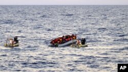 Photo provided by the Italian Navy shows rescue crews approaching migrants on a rubber boat some 40 miles (65 kilometers) from the Libyan capital, Tripoli.