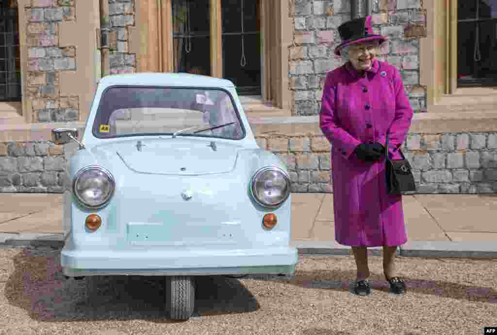 Britain's Queen Elizabeth II stands beside the classic invalid carriage, as she hosts a ceremony to celebrate the 40th Anniversary of Motability, at Windsor Castle, west of London.