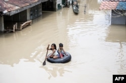 Children use a tyre's interior to cross a flooded street in the aftermath of Super Typhoon Mangkhut at Salonga Compound in Calumpit, Bulacan on September 16, 2018.