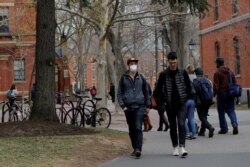 Seorang mahasiswa yang mengenakan masker, karena pengobatan kankernya telah membuatnya tertekan kekebalan dan rentan terhadap penyakit seperti virus corona, berjalan melalui Halaman di Universitas Harvard. (Foto: Reuters)