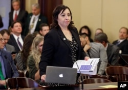 FILE - Utah state Rep. Angela Romero prepares to testify at the State Capitol in Salt Lake City about a plan to give state and higher education workers six weeks of paid leave when they become new parents, Feb. 18, 2016. A legislative panel, citing cost concerns, voted to study the bill between sessions.