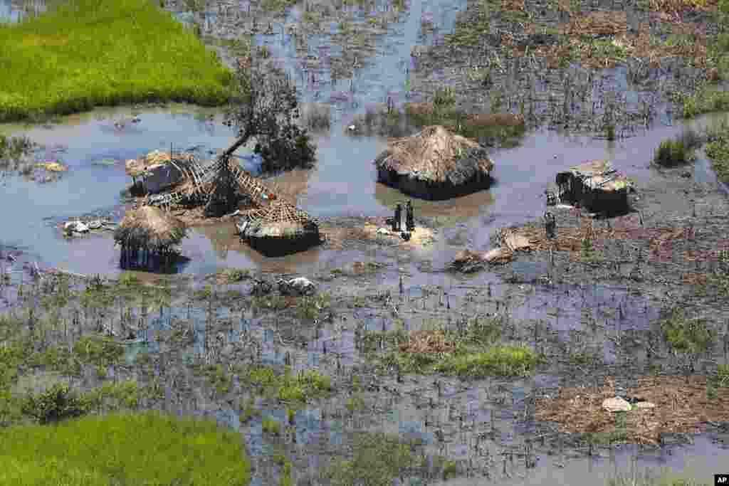 A family stand outside their submerged huts near Nhamatanda, about 130km from Beira, in Mozambique, March, 26, 2019.