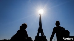 Sejumlah turis menikmati pemandangan Menara Eiffel di lapangan Trocadero di tengah cuaca cerah di Paris, Prancis, 3 September 2021. (Foto: Eric Gaillard/Reuters)