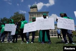 Un grupo de jóvenes sostiene carteles durante una vigilia en honor de las víctimas de un tiroteo masivo en Dayton, Ohio, el domingo 4 de agosto de 2019. REUTERS/Bryan Woolston.