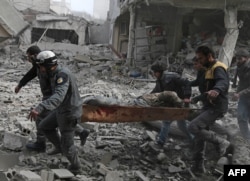 Members of the Syrian civil defence evacuate an injured civilian on a stretcher from an area hit by a reported regime air strike in the rebel-held town of Saqba, in the besieged Eastern Ghouta region on the outskirts of the capital Damascus.