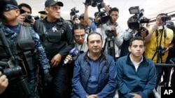Jose Manuel Morales, the son of Guatemala's President Jimmy Morales, right, and his uncle Samuel "Sammy" Morales, center, sit in a courtroom in Guatemala City, Jan. 18, 2017. Both are being investigated for their involvement in a corruption case. 