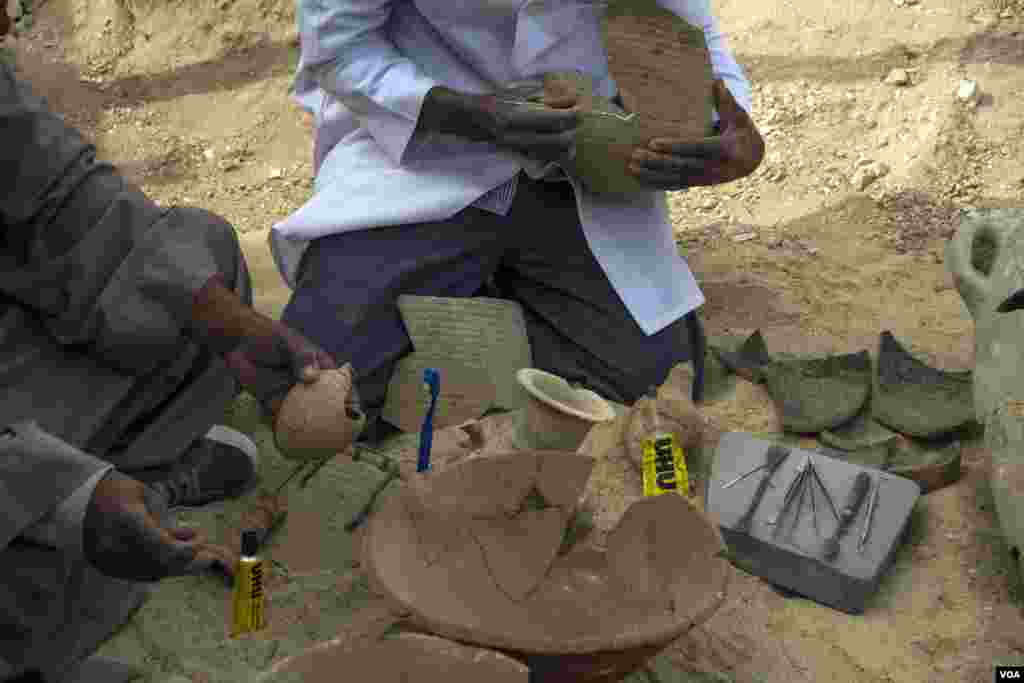 Para pekerja penggalian memulihkan bejana-bejana dengan berbagai bentuk di makam yang baru ditemukan di pekuburan Draa Abul Naga, di Tepi Barat Luxor, Mesir, 9 Desember 2017. (H. Elrasam/VOA)