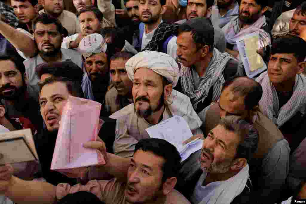 Afghans gather outside the passport office after Taliban officials announced they will start issuing passports again in to citizens, following months of delays that hampered attempts by those trying to flee the country after the Taliban seized control, in Kabul, Afghanistan.