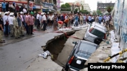 ​​Onlookers watch the cars sink in a hole by a construction site by Phnom Penh's Olympic Stadium after a heavy rain on Wednesday, June 8, 2016. (Courtesy of SBN)