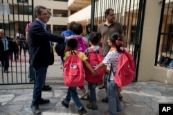 FILE - Refugee children enter a primary school in Athens on the first day of lessons under the new refugee schooling program, Oct. 10, 2016.