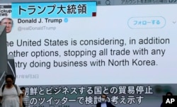 FILE - People walk by a TV news program showing a tweet, issued by U.S. President Donald Trump, during a report on a North Korean nuclear test, in Tokyo, Sept. 4, 2017.