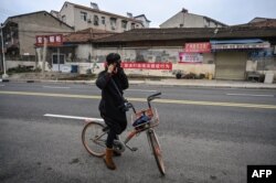 A woman puts a protective mask in a neighborhood on the outskirts of Wuhan in China's central Hubei province on January 27, 2020, amid a deadly virus outbreak which began in the city.