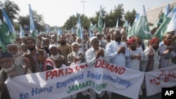 Supporters of the religious and political party Jamaat-e-Islami hold a banner that reads 'Pakistani Demand to Hang Raymond Davis Immediately' while praying during a protest rally in Karachi, January 30, 2011.