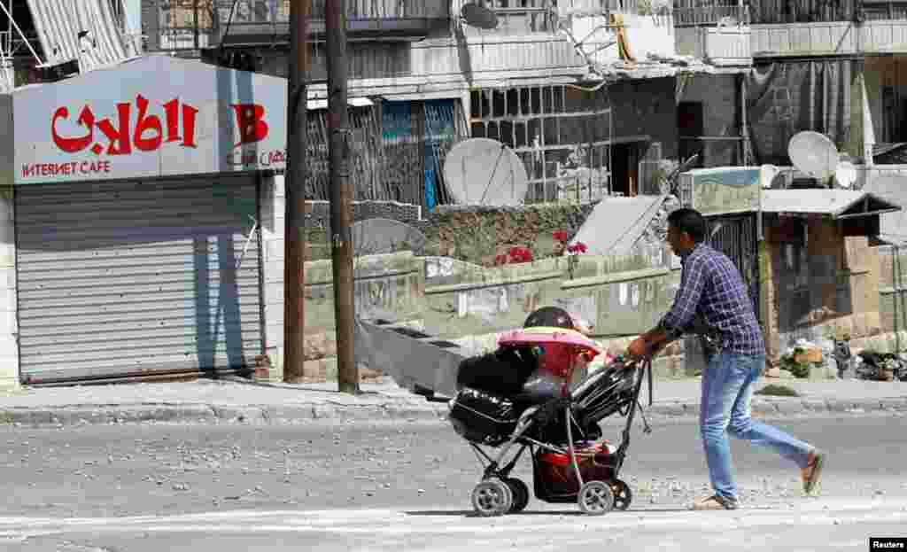 A civilian pushes a baby stroller containing his belongings as he flees the El Edaa district in Aleppo, September 2, 2012. 