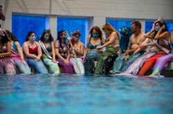 Mermaids dan Mermen berkumpul di sekitar kolam renang utama untuk foto bersama saat berlangsungnya MerMagic Con di Freedom Aquatic Center, Manassas, Virginia, 7 Agustus 2021. (AFP)
