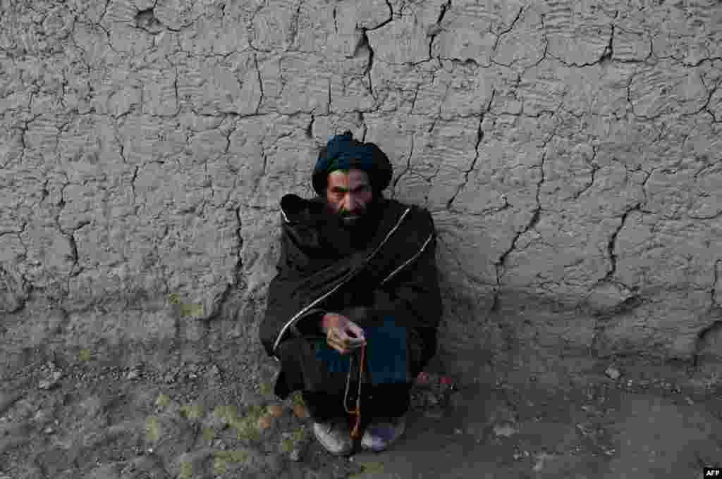 An internally displaced Afghan man prays as he sit at a refugee camp in Kabul.