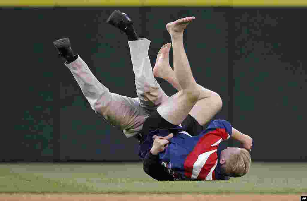 A ballpark security worker, left, tackles a fan who ran onto the outfield during a baseball game between the Seattle Mariners and St. Louis Cardinals, in Seattle, Washington, USA, June 25, 2016.