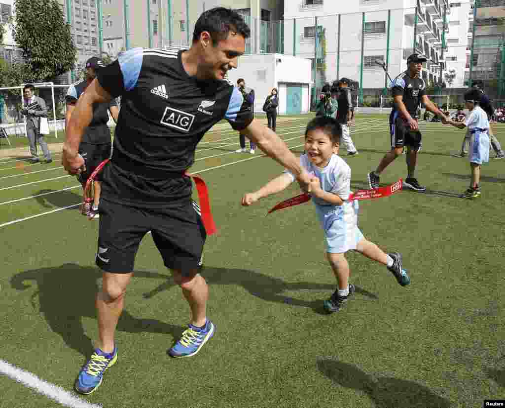 New Zealand All Blacks' Daniel Carter plays tag rugby with a student as the All Blacks visit Aoyama Elementary School ahead of Saturday's international friendly rugby match against Japan in Tokyo. 