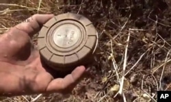 FILE - A volunteer deminer takes a landmine from the ground in Daraa, Syria, in this still image made from video taken Sept. 7, 2015, provided by the Syrian Center for Demining and Rehabilitation.