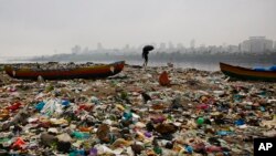 Seorang nelayan India berjalan di pantai Laut Arabia yang penuh dengan sampah di Mumbai (foto: dok). Pemerintah India hari Minggu (2/10) meratifikasi perjanjian iklim yang disepakati di Paris.