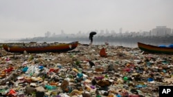 A fisherman walks on the shores of the Arabian Sea, littered with plastic bags and other garbage, in Mumbai, India, Oct. 2, 2016. 