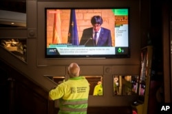 People in a bar watch the speech of Catalan regional president Carles Puigdemont on television in Barcelona, Spain, Thursday, Oct. 26, 2017.