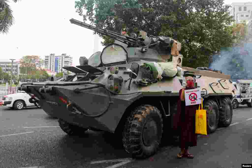 A Buddhist monk holding a sign stands next to an armored vehicle during a protest against the military coup, in Yangon, Myanmar.